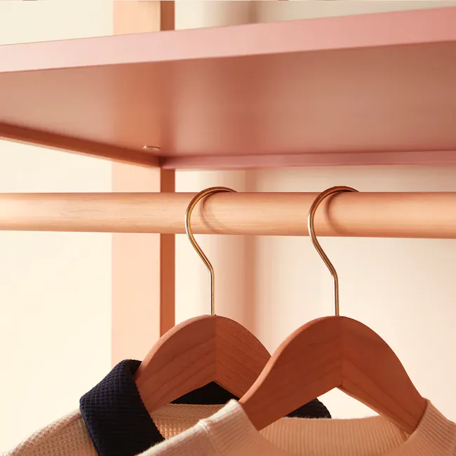 Tidy Storage Bookcase - Barley White & Almond - 7 - Copper-colored rod, wooden hangers, beige and dark blue sweater, light