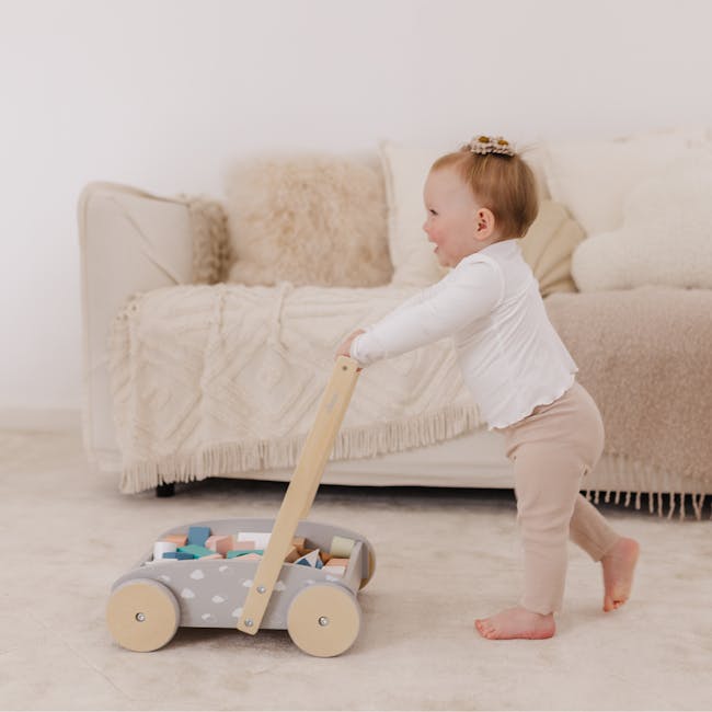 Bubble Wooden Baby Push Cart with 45 Buiding Blocks - 3 - Baby in white shirt and beige pants, pushing a toy wagon with