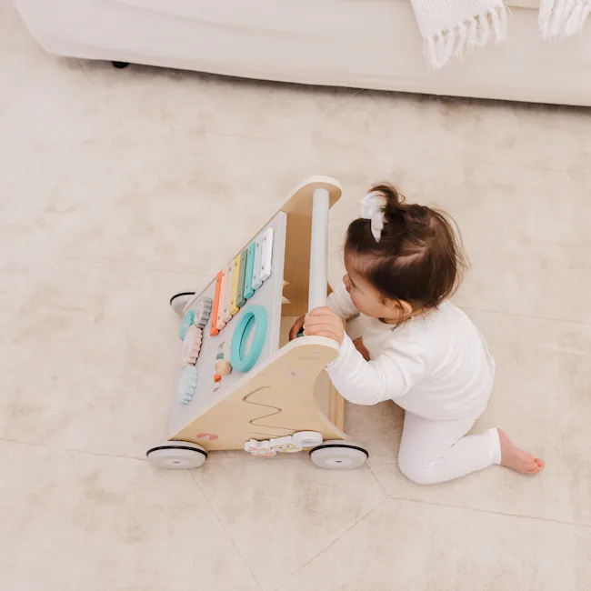 Bubble Wooden Activity Play Walker - 10 - White, child, white outfit, brown hair, white socks, beige carpet, wooden toy