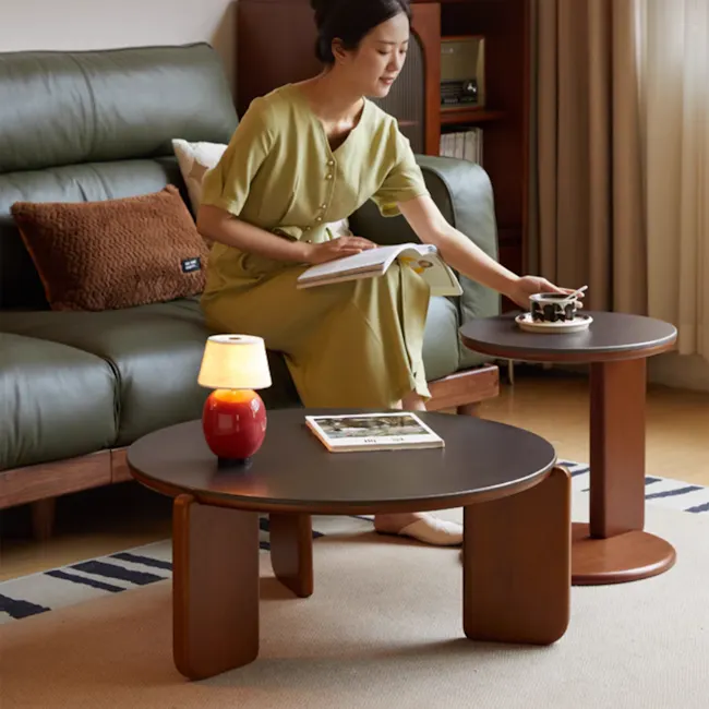 Blair Round Side Table - Walnut, Black (Sintered Stone) - 9 - Sitting on green leather sofa, woman in olive green dress