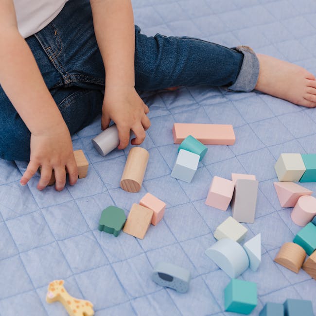 Bubble Wooden Activity Blocks - 12 - Child's hands playing with wooden blocks, blue grid-patterned surface, pastel-colored