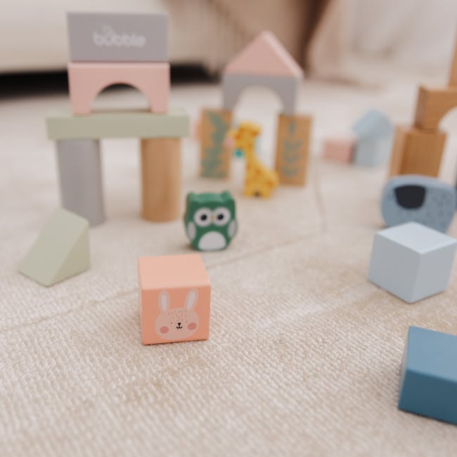 Bubble Wooden Activity Blocks - 8 - Soft pastel-colored wooden toys, including a bunny, owl, and giraffe, scattered on a