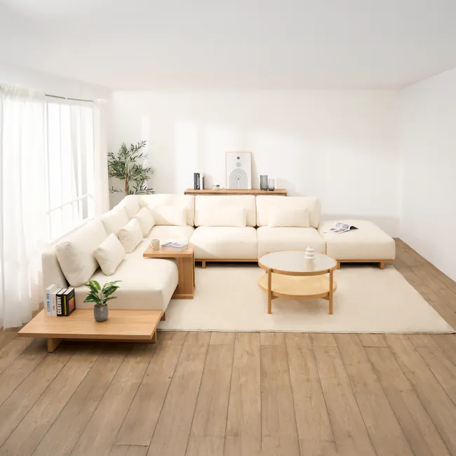 Miu Side Ottoman - 9 - Minimalist living room with white walls and wooden flooring, featuring a large beige sectional sofa
