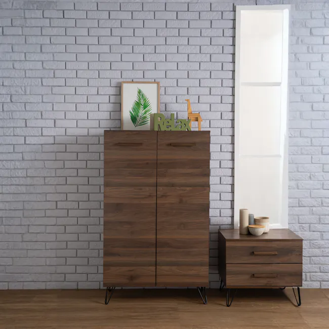 Sandra Shoe Cabinet - Walnut - 5 - Wooden cabinet with black metal legs, gray brick wall background, green leafy plant