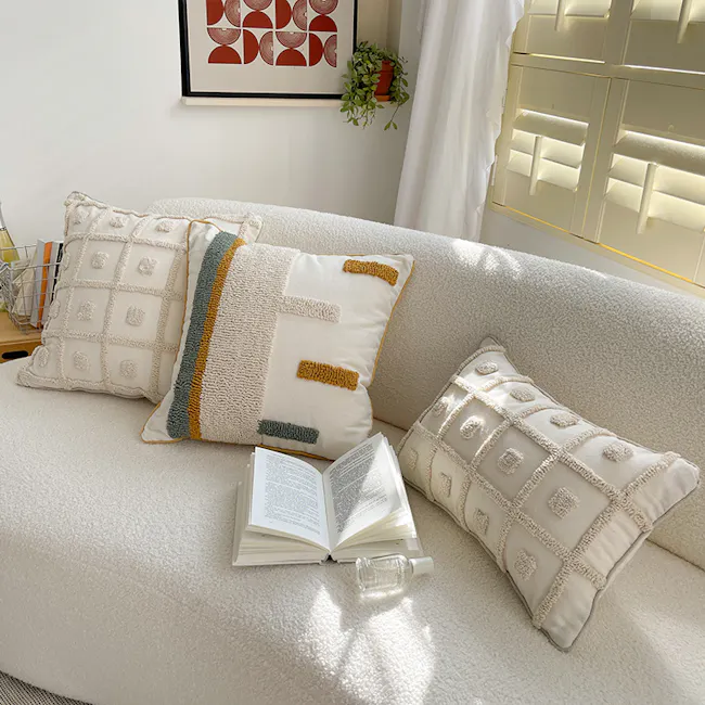 Alivia Cushion Cover - 2 - White textured sofa, cozy reading nook, soft cushions, geometric patterned pillows, open book