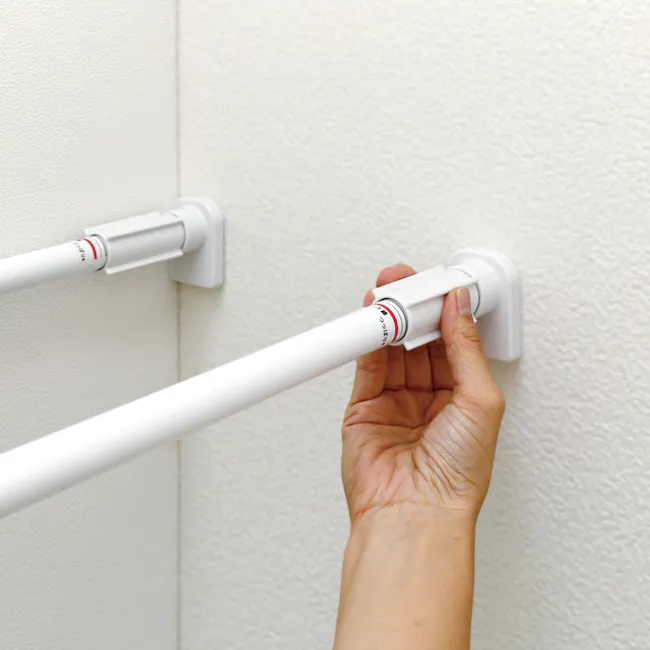 HEIAN DIY Extension Shelf - 73cm to 112cm - 5 - Hand holding white wall-mounted grab bar, white wall, textured wall, white