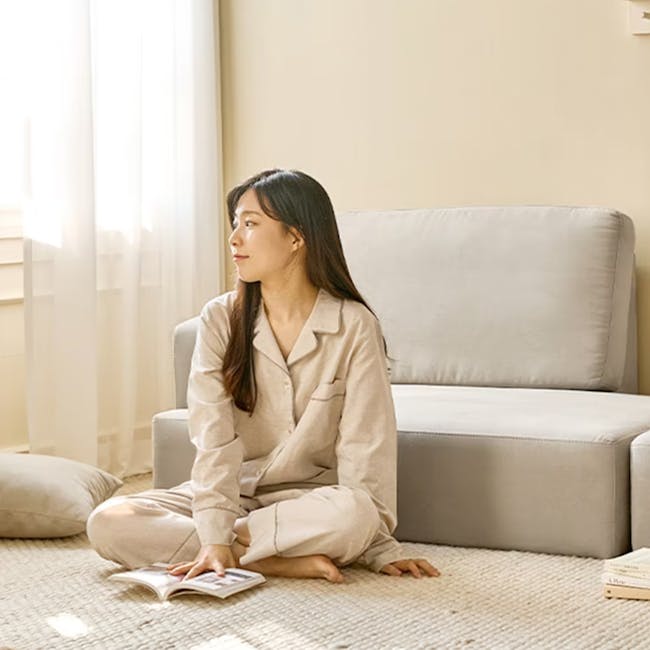 Genevieve 2 Seater Chaise Sofa with Ottoman - Grey (Pet Friendly) - 6 - Sitting on a beige sofa, woman in beige pajamas