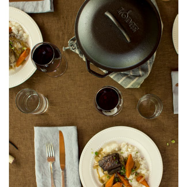 Lodge Seasoned Cast Iron Dutch Oven (2 Sizes) - 4 - White plate with grilled meat, orange carrot slices, green onions, dark