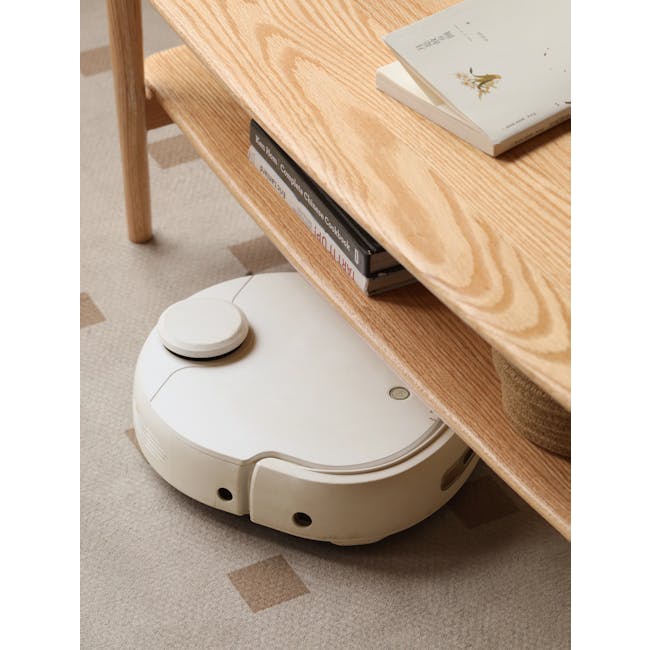 Nigel Narrow Coffee Table 1.2m - 13 - Wooden coffee table, stack of books, white robotic vacuum cleaner, beige carpet