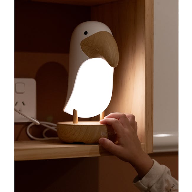 Bubble Toucan Night Light - 9 - Wooden bird lamp, glowing light, child's hand, wooden base, white bird head, wooden stand