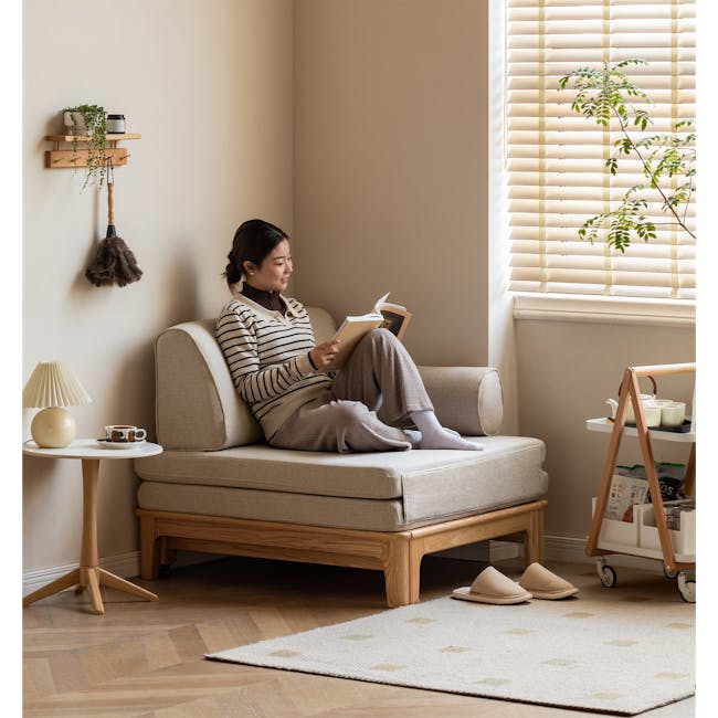 Zara Sofa Bed - Gravel White - 4 - Sleek wooden side table, beige sofa, woman reading book, light brown wooden floor, wooden