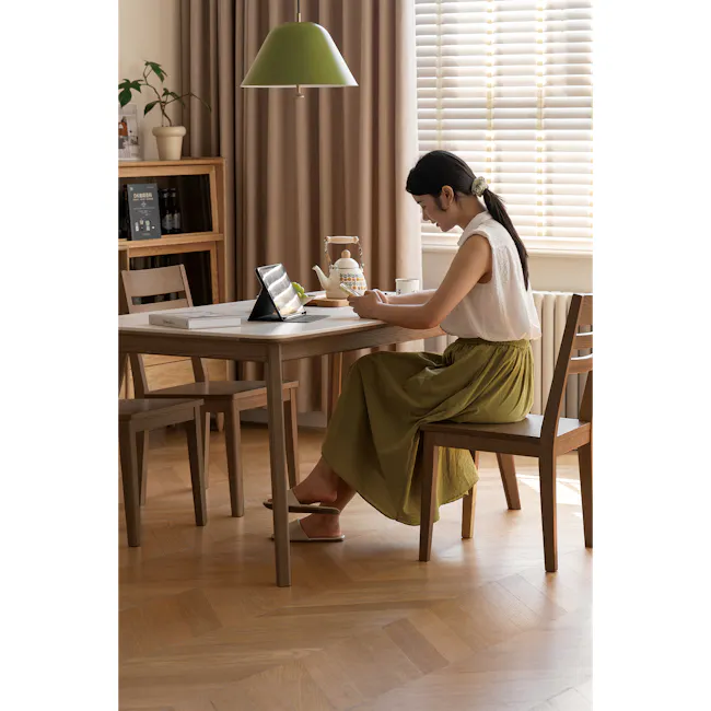 Nellie Dining Table 1.8m - Walnut (Sintered Stone) - 4 - Wooden dining table, woman sitting, laptop on table, green pendant