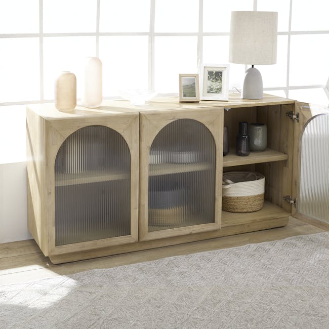 Catania Sideboard 1.6m - 3 - Light wood cabinet with glass doors, beige vase, white lamp, framed photo, woven basket