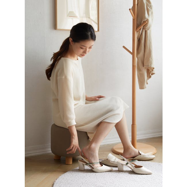Niyo Stool - Cream - 5 - White textured sweater, beige pants, wooden stool, beige shoes with green ankle straps, wooden coat