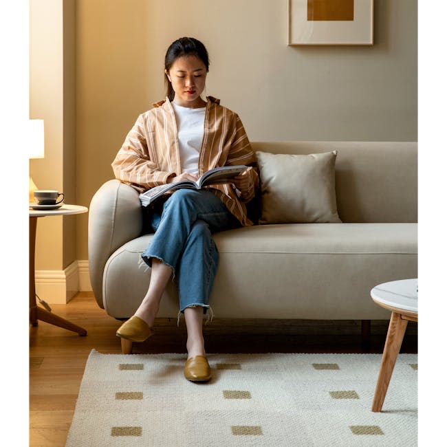 Miko 2 Seater Sofa - Rice White (Pet Friendly) - 2 - Sitting on beige sofa, reading magazine, wearing striped shirt, blue