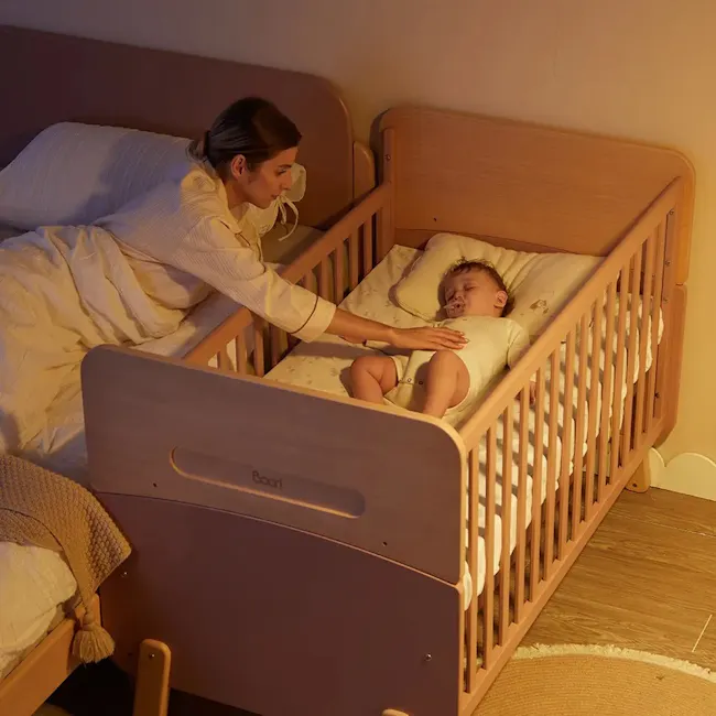 Neat Boori 5 in 1 Cot Bed - Cherry - 5 - Sleepy baby peacefully sleeping in crib, woman gently touching baby's face, wooden