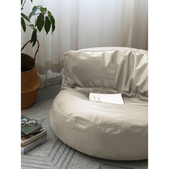August Round Bean Bag - Rice White (Faux Leather) - 3 - Sleek beige cushion, stacked books, pair of glasses, soft natural