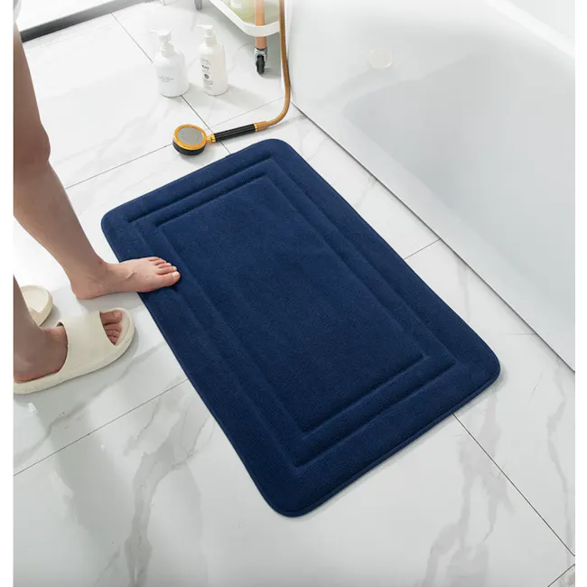 Lexi Bath Mat - Navy - 3 - blue bath mat, white marble floor, person standing, white bath products, white wall tiles, white