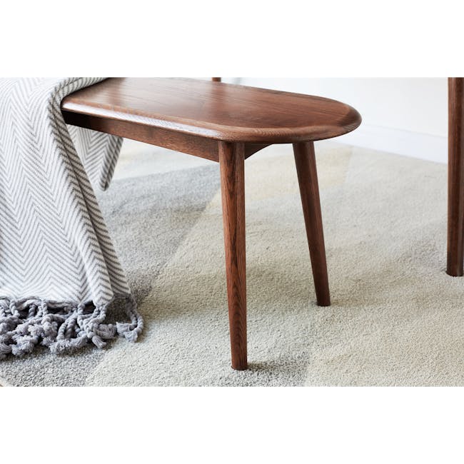 Felda Bench 1m - Walnut - 7 - Wooden table with chevron pattern, gray and white blanket, wooden legs, beige carpet, textured