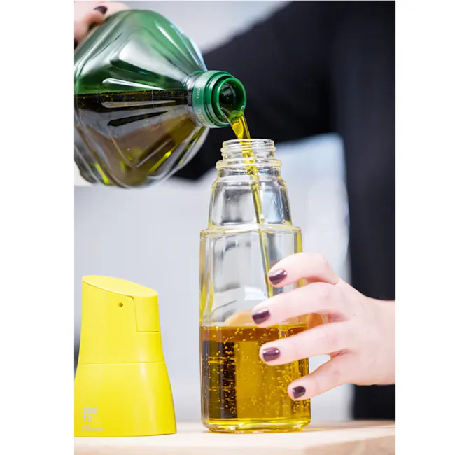 Zuutii Drip-Free Oil Carafe - Lemon Yellow - 11 - Green bottle pouring olive oil, yellow bottle with oil, person's hand with