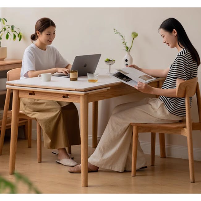 Fidela Extendable Dining Table 0.9m-1.5m (Sintered Stone) - 7 - Two women working on laptops in a cozy home office setting.