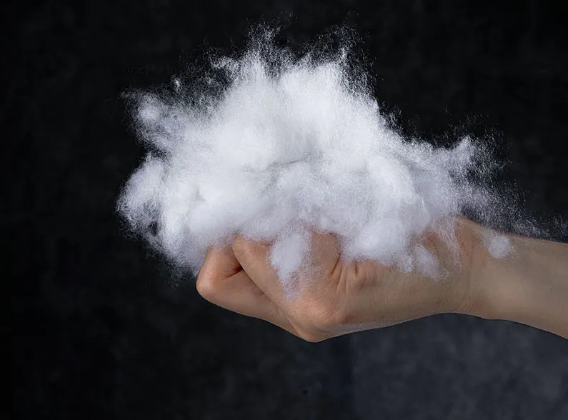 Tanisha Textured Waffle Weave Cushion - Cream - 10 - Hand holding fluffy white cotton, dark background, close-up view