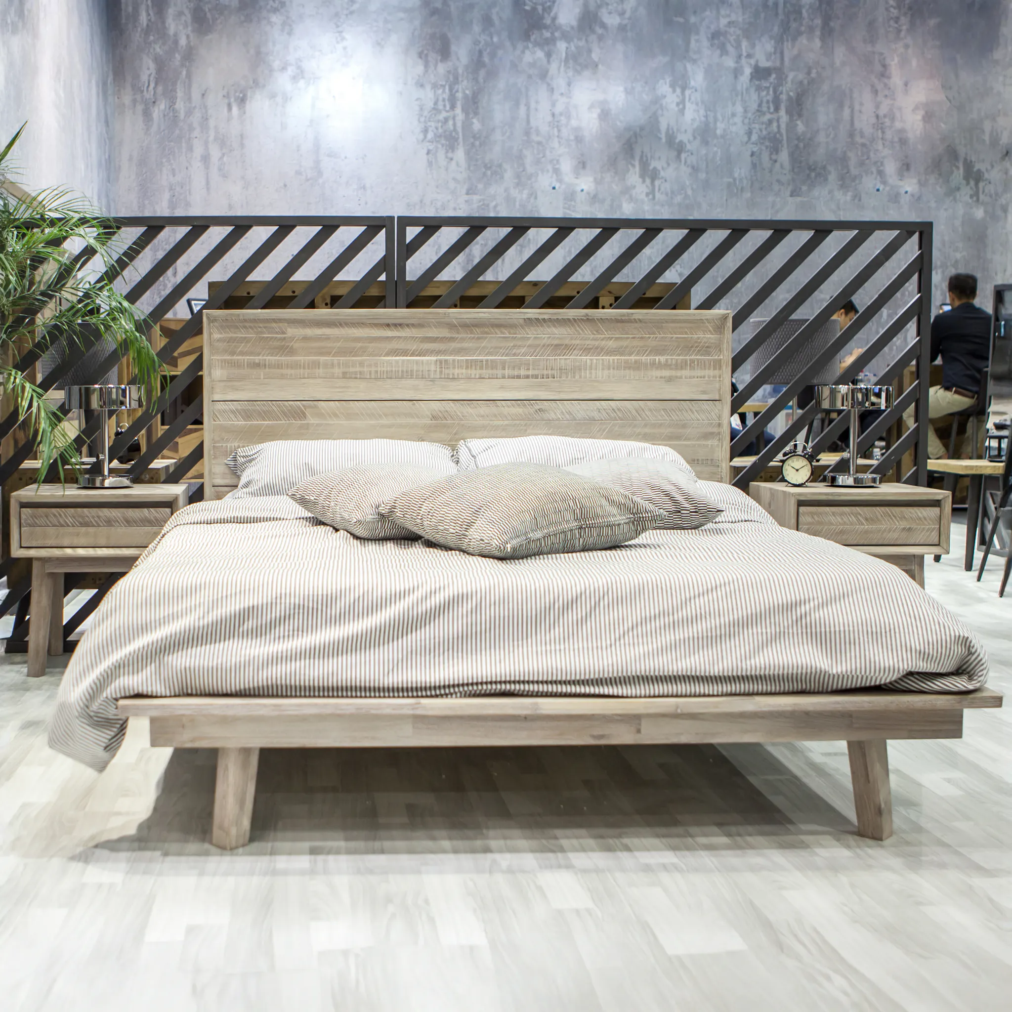 Leland King Platform Bed - 10 - Wooden bed with striped bedding, modern bedside tables, black metal railing, indoor plant
