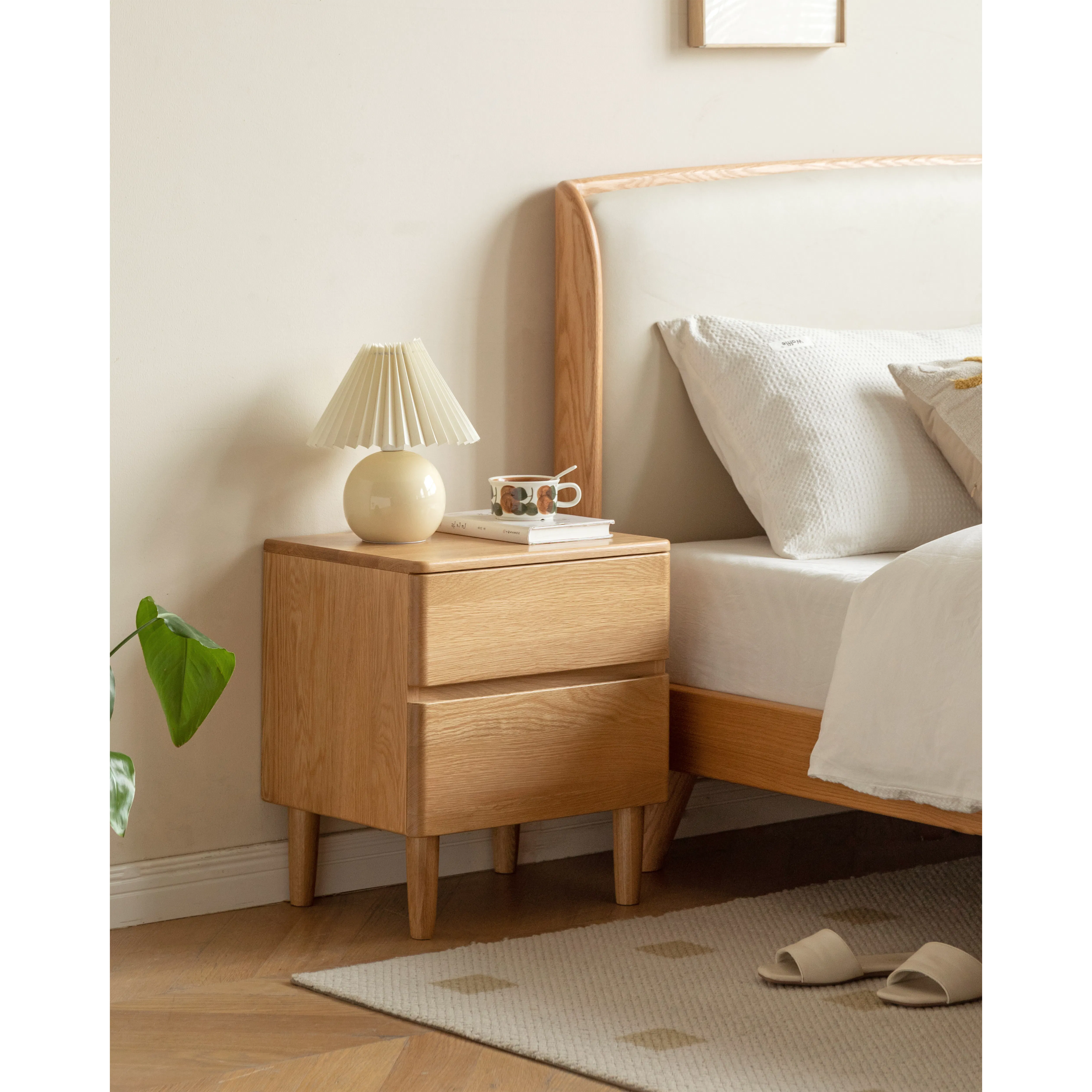 Natalia Bedside Table - 11 - Wooden nightstand, beige lamp, white cup, white pillows, wooden headboard, light beige wall