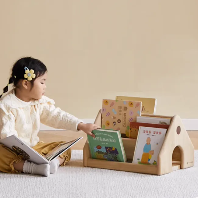 Micah Wooden Kids House Book Organiser - 2 - Little girl in yellow dress sitting on carpet, reading book, holding open book