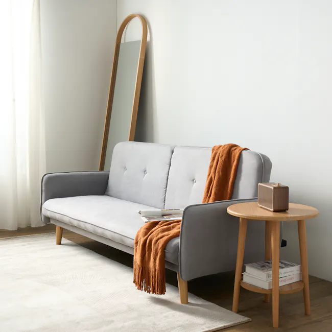 Emery 3 Seater Sofa Bed - Pigeon Grey - 4 - Light gray sofa, wooden legs, white and orange throw blanket, round wooden