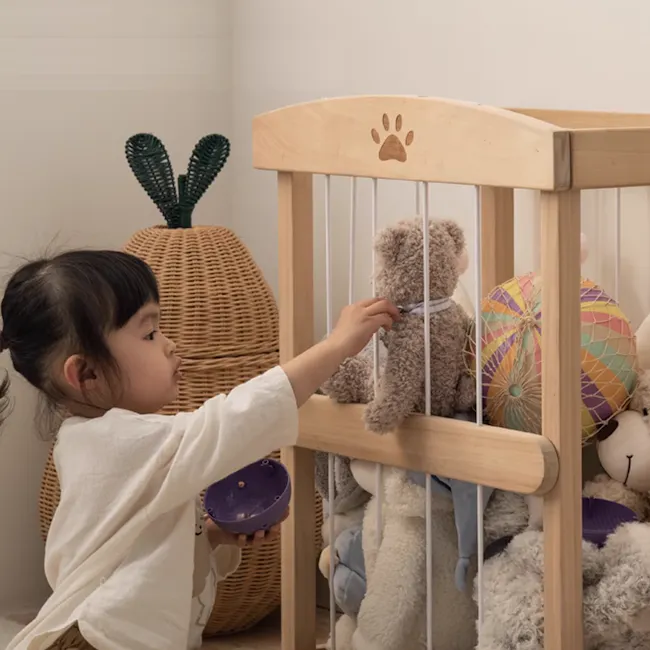 Micah Wooden Kids Toy Storage - 2 - Little girl painting a teddy bear with a purple brush, wearing a white shirt, sitting on