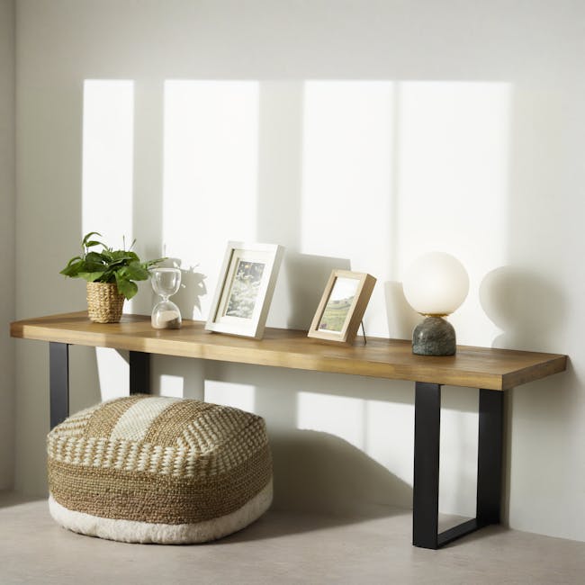 Ora Table Lamp - Dark Jade - 2 - Sunlight casts shadows on the wall, creating a serene atmosphere. A woven basket holds a