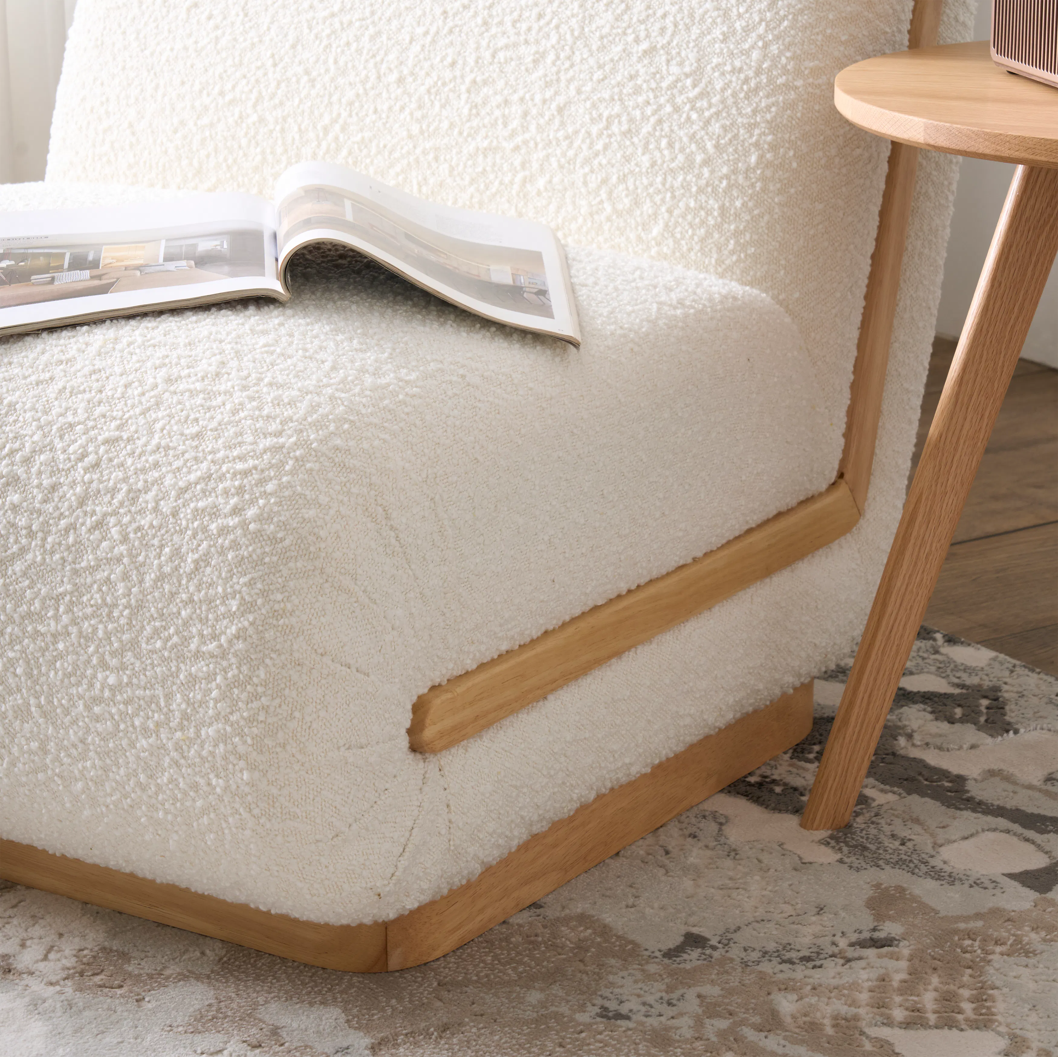 Eloise Lounge Chair - 14 - Soft, white, textured armchair with wooden legs, open magazine on armrest, cozy room ambiance