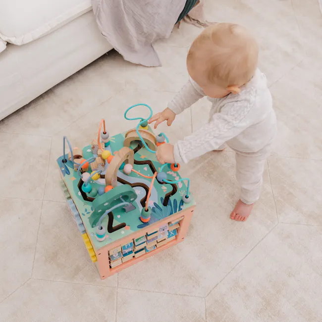 Bubble Wooden Activity Centre - 7 - Baby playing with colorful toy, indoor setting, light-colored carpet, wooden toys, blue