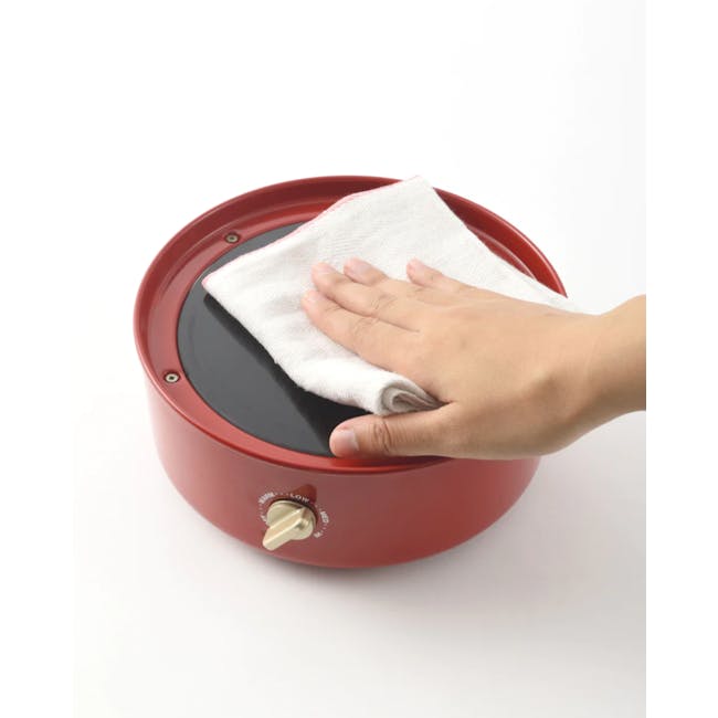 BRUNO Grill Pot - Pale Pink - 6 - Red electric pressure cooker, white cloth, hand pressing down, fabric softener dispenser