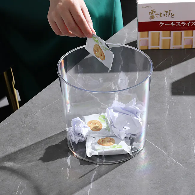 Gabri Waste Bin - 4 - Clear glass bowl, crumpled paper, Japanese text, clear plastic, person's hand, cookie wrappers, green