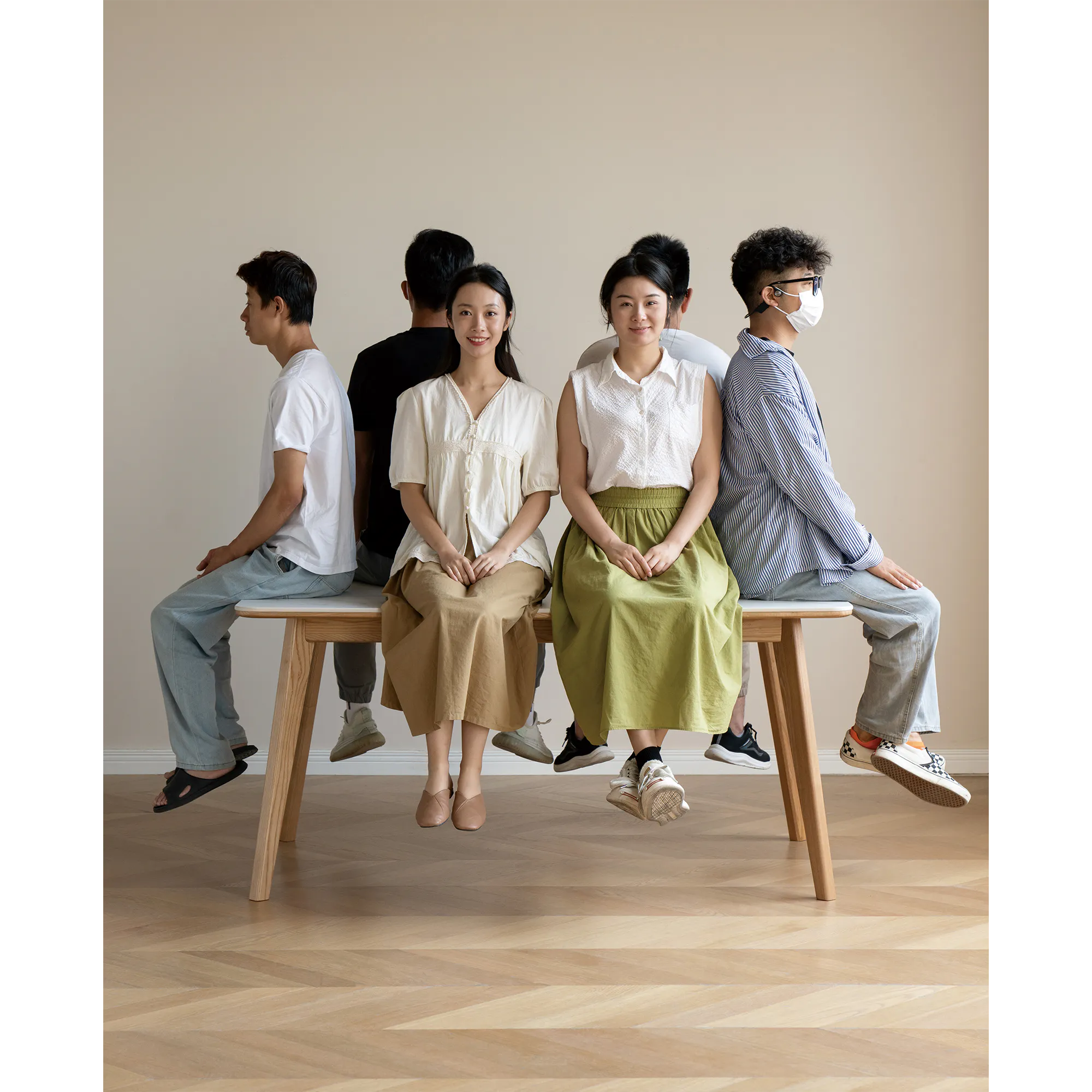Nellie Dining Table 1.4m - Oak (Sintered Stone) - 29 - Group of people sitting on a bench, wearing casual clothing, smiling