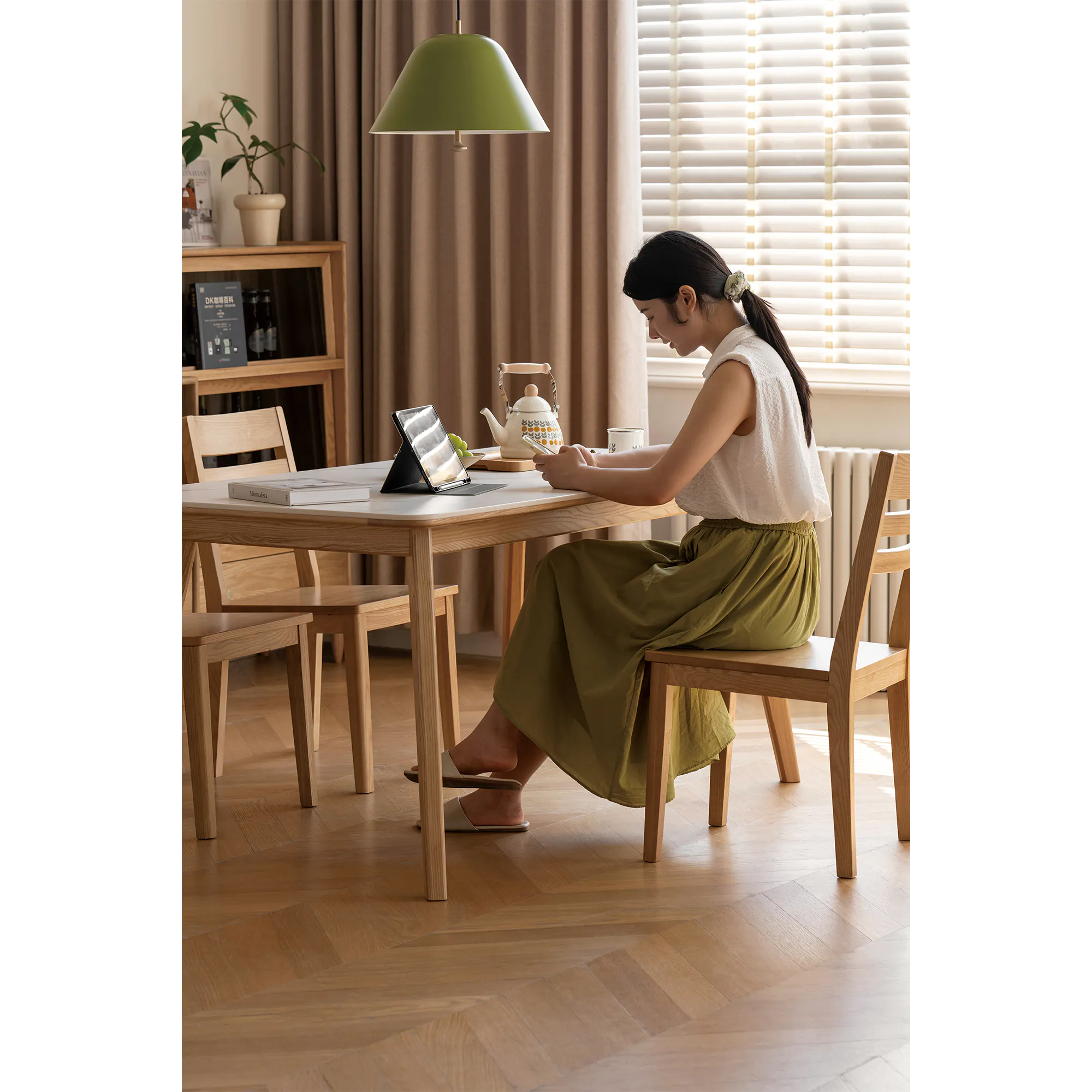 Nellie Dining Table 1.4m - Oak (Sintered Stone) - 14 - Wooden dining table, woman sitting, laptop on table, green pendant