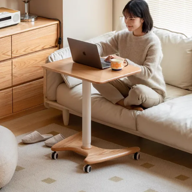 Easton Adjustable Table 0.6m - Oak, White - 3 - Sitting on a cozy beige sofa, woman in light gray sweater working on laptop