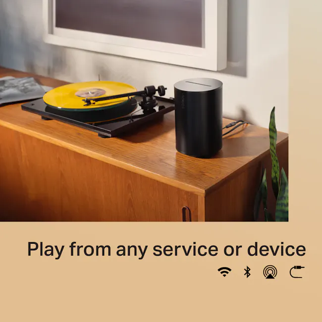 Sonos Era 100 - Black - 7 - Vinyl record on turntable, black speaker, modern room decor, wooden cabinet, green plant