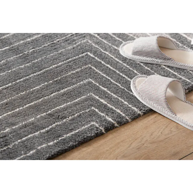Fjord High Pile Rug - Dark Symmetry (2 Sizes) - 3 - Gray and white striped rug, light-colored slippers, wooden floor, cozy