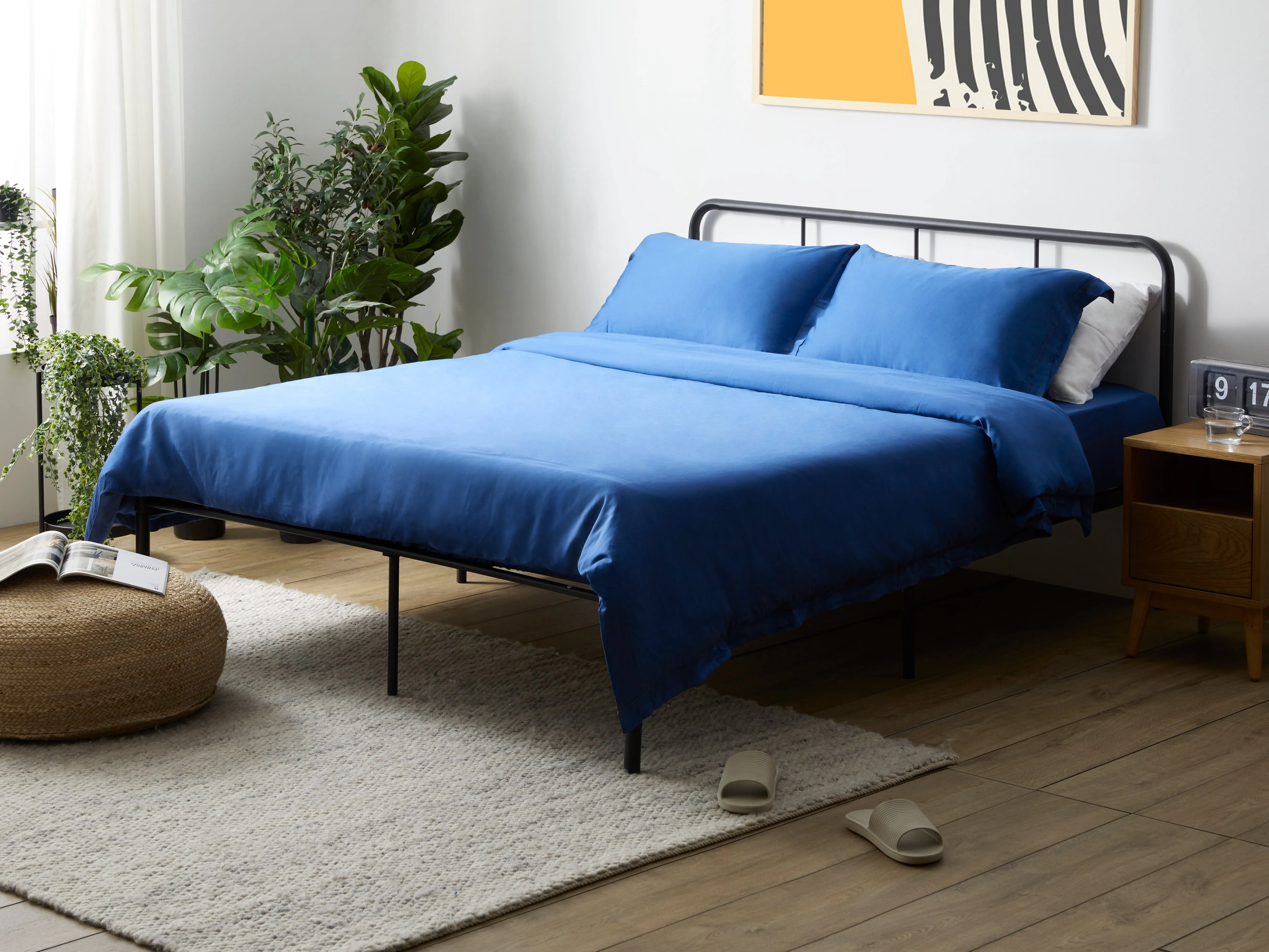 Owen Single Metal Bed - Black - 12 - Blue bed with white pillows, modern bedside table, beige slippers on floor, wooden