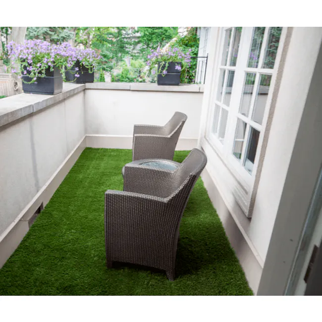Patio Grass Carpet - 4 - Green artificial grass patio, gray wicker chairs, potted purple flowers, white wall, large window