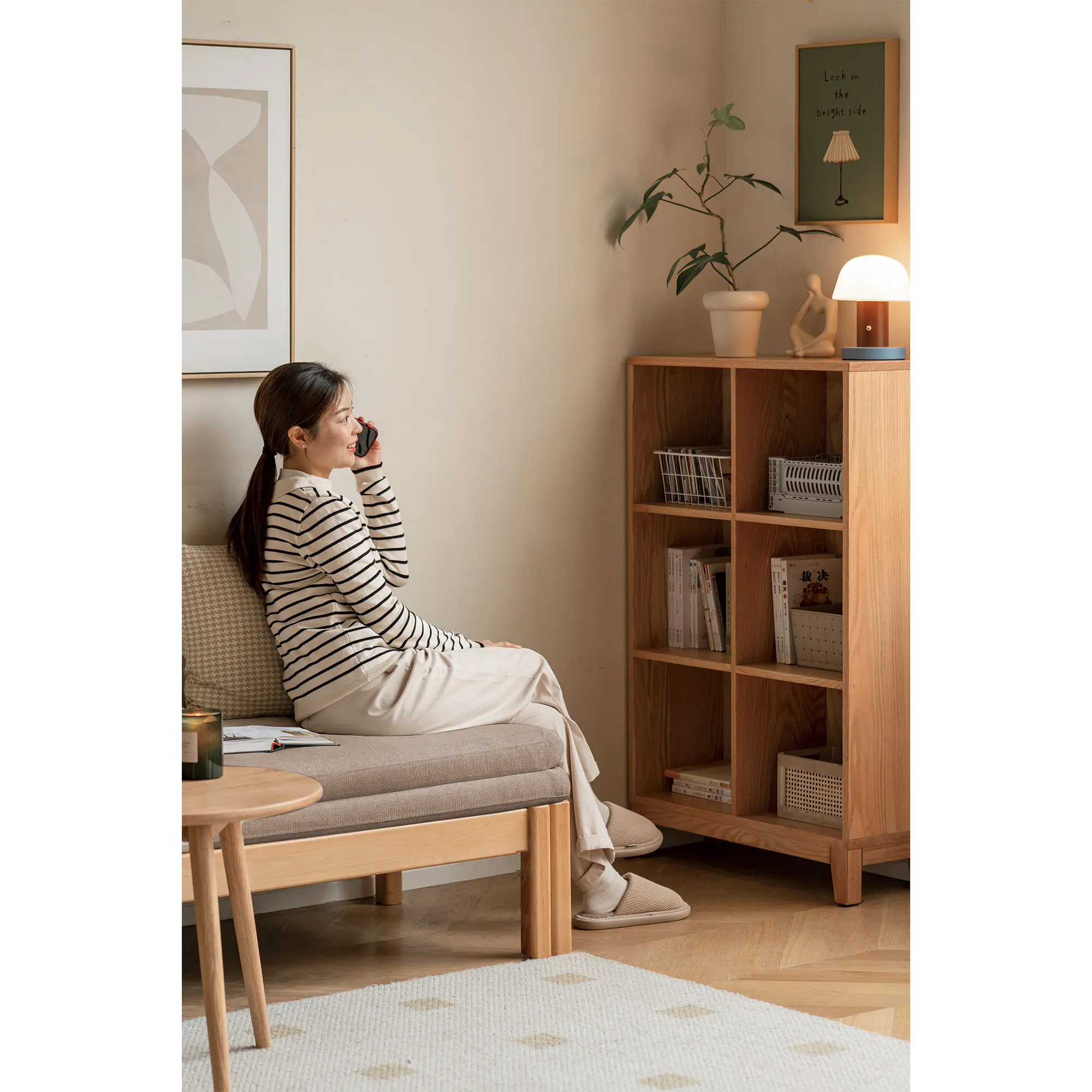 Cleo Sofa Bed / Bench 2m - Chestnut - 17 - Sitting on a cushion, woman talking on phone, light beige wall, framed abstract