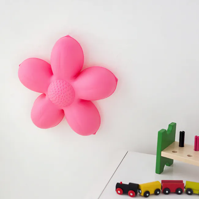 Kids Blossom Flower Wall Lamp - 5 - Bright pink flower-shaped toy on white wall, Green and wooden toy table with black and