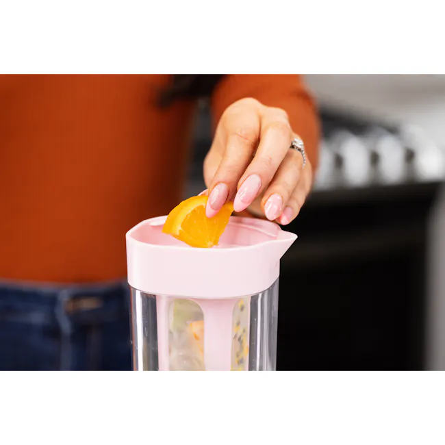 Zuutii Infuser Pitcher - Sakura Pink - 5 - Orange slice, pink nail polish, juicer, kitchen countertop, person's hand, orange