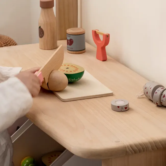 Micah Wooden Kids Toy Grocer Stand - 5 - Wooden kitchen utensil, child's hand, wooden cutting board, green bowl, wooden