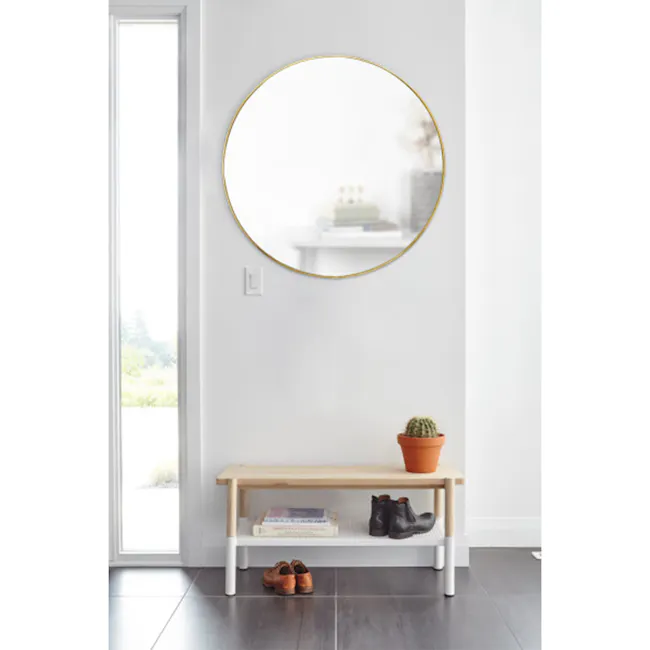 Hubba Round Mirror 86 cm - Brass - 6 - Modern minimalist interior, white walls, large circular mirror, wooden bench, potted