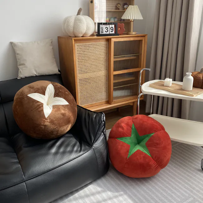 Tomato Plush Cushion - 4 - Rustic wooden cabinet with a black leather sofa and two plush cushions, Pumpkin-themed decor on a
