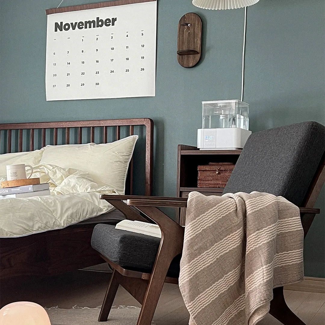 Aston Armchair - Seal - 14 - Wooden nightstand, white calendar, blue wall, wooden chair, beige blanket, gray cushion, wooden